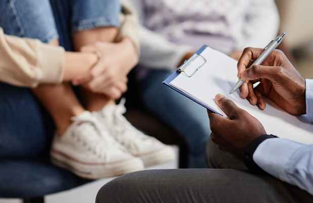 therapist writing on clipboard with child in background