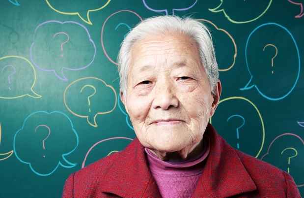 Elderly Asian woman standing in front of a graphic with speech bubbles