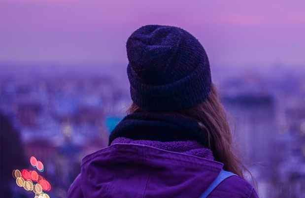 hipster girl looking out into the city at dusk
