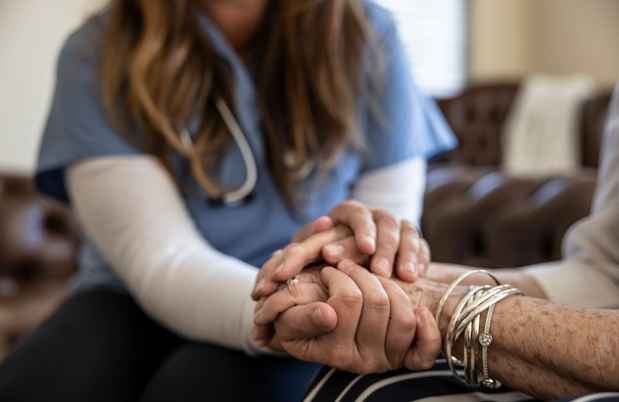 Nurse holds patient’s hands