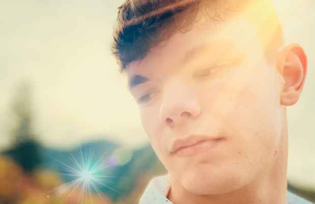 Adolescent looking down with sun shining