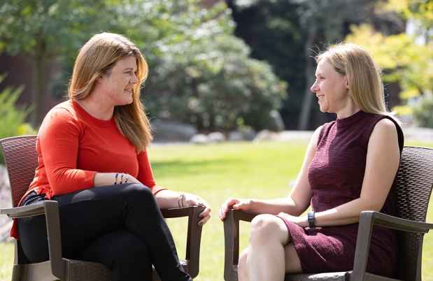 Two women smiling and sitting in chairs
