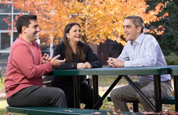 Group of people sitting and smiling at a table outside