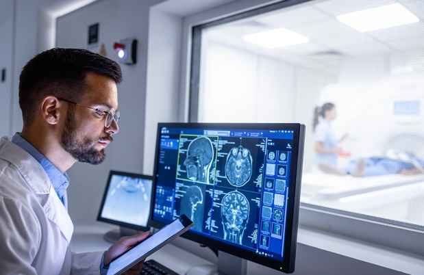 Man looks at computer showing brain scans