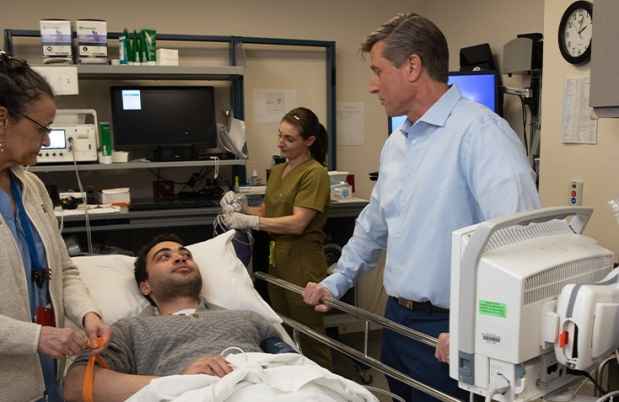 Doctor talks with patient in room with medical equipment