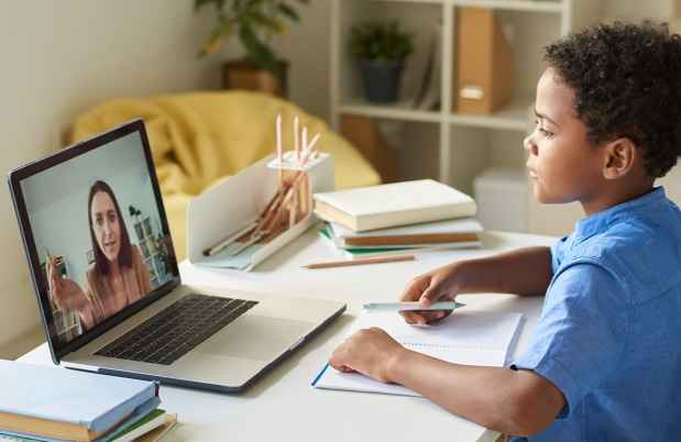 Boy sits at desk with a laptop