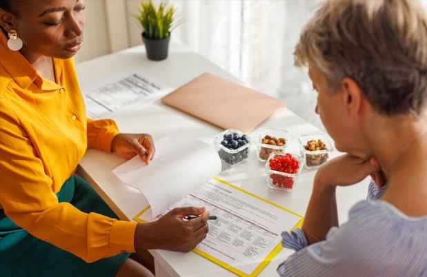 Female nutritionist discussing fruit portions with elder patient