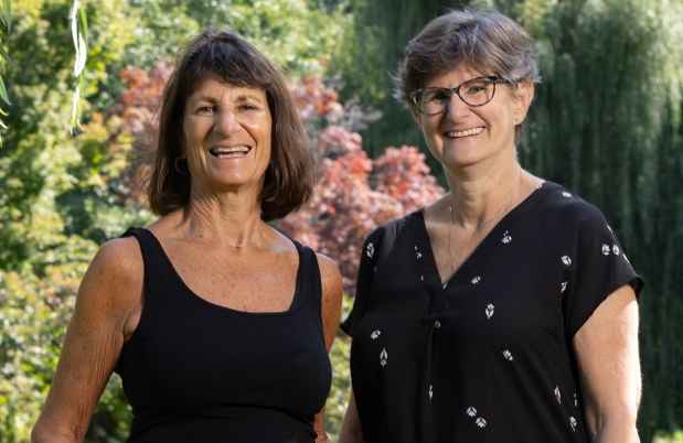 Two sisters in black shirts pose outside