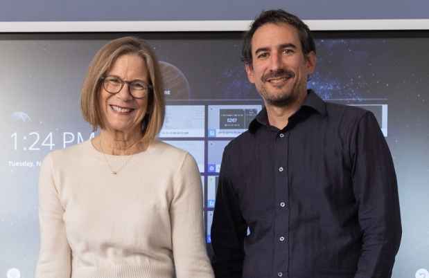 Two educators stand in front of smartboard