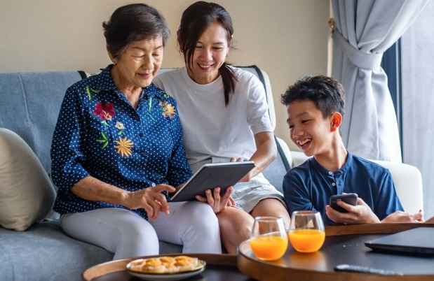 Multi generation family using digital tablet on sofa