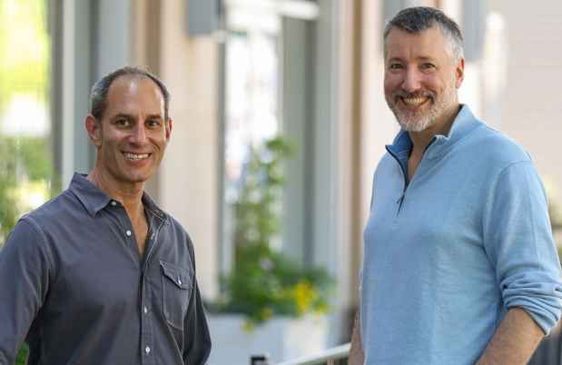 Two men pose outside a building