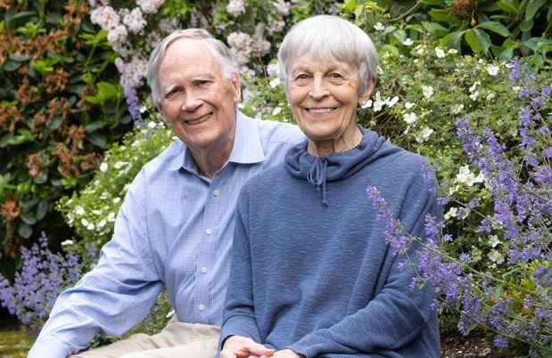 Two older adults sit outside in a garden