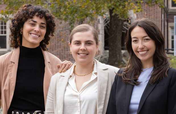 3 young professionals pose outside brick buildings