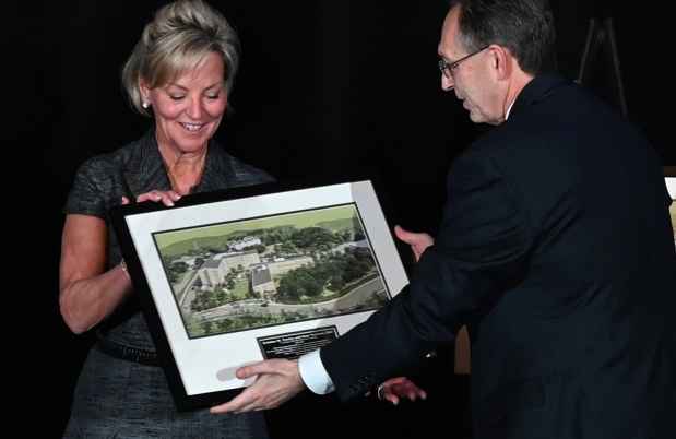 One person hands framed rendering to another person at a award ceremony