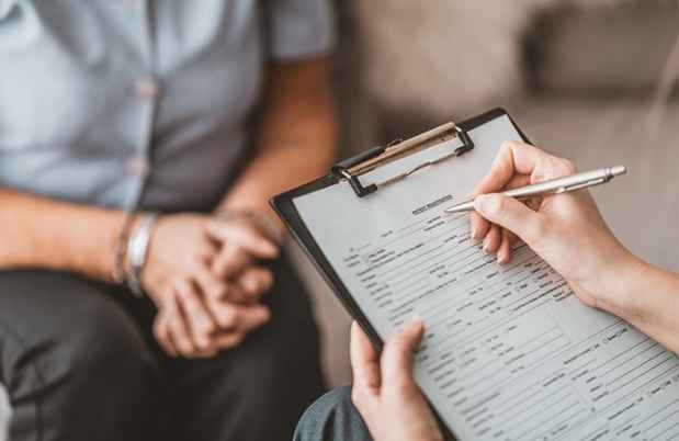 Close up of nurse fills out patient paperwork with patient