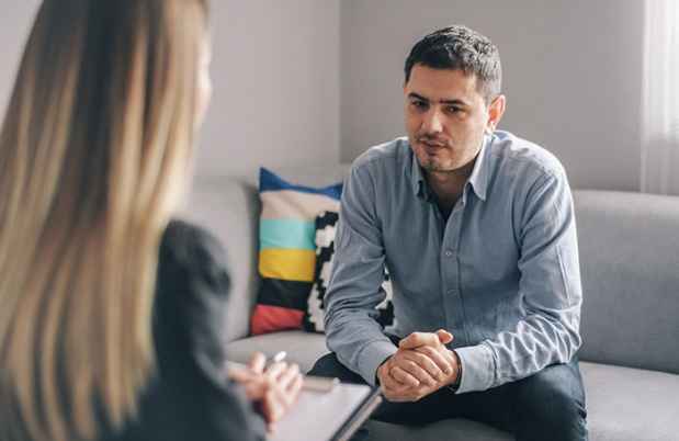 Man sits on couch talking to therapist