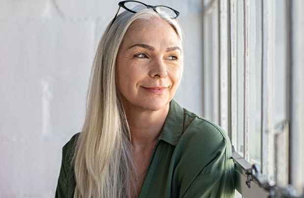 Woman with long gray hair and glasses on top of head