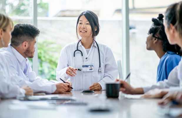 Doctor speaks with trainees at conference table