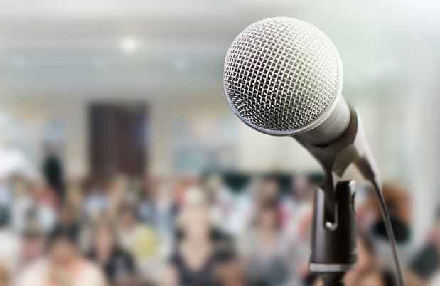 Stock photo of microphone with blurry audience in background