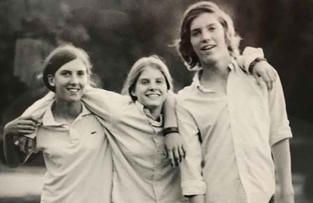 Black and white image of siblings with arms around each others necks