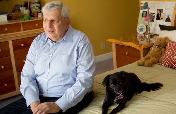Man and dog sit on bed