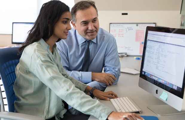 Research assistant and investigator look at data on a computer screen