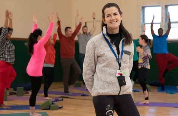 Woman poses in front of yoga class in gym
