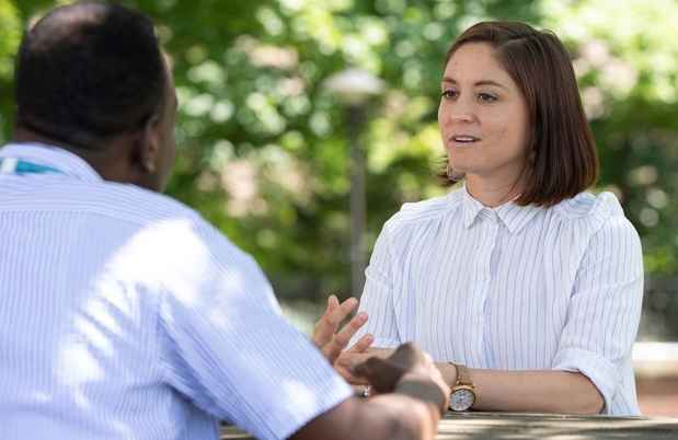 Woman speaks with male clinician while they sit outside