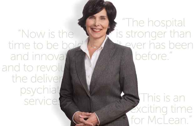 Carol Vallone stands in front of white background with gray quotes