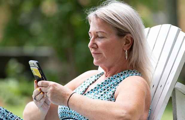Woman sits and looks at smartphone