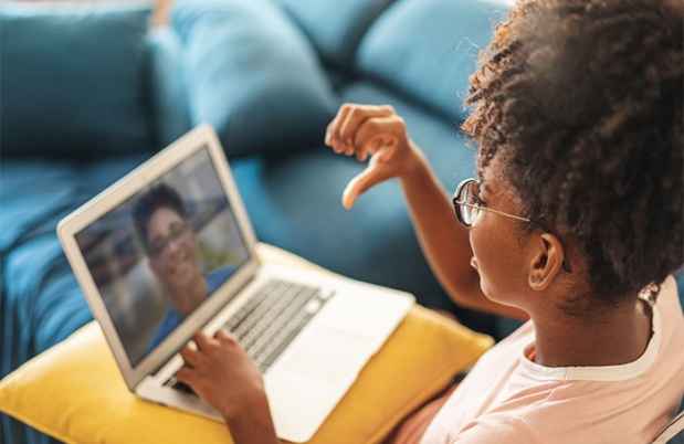 Young girl talks to teacher via computer