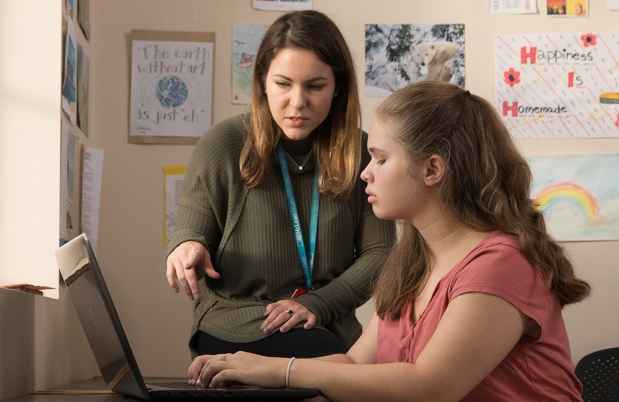 Clinician points at laptop while teen is typing