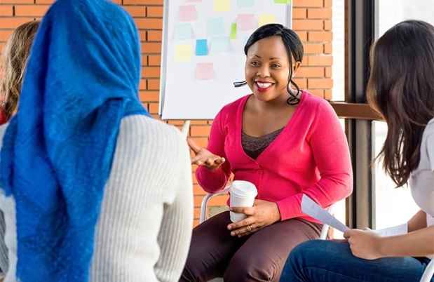 African american woman in a pink sweater talking to a group