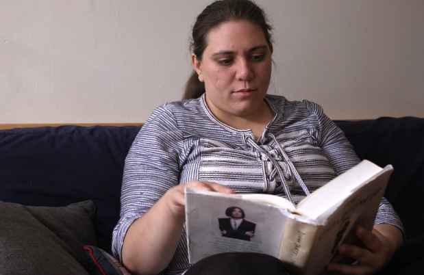 Patient Becca sits reading book