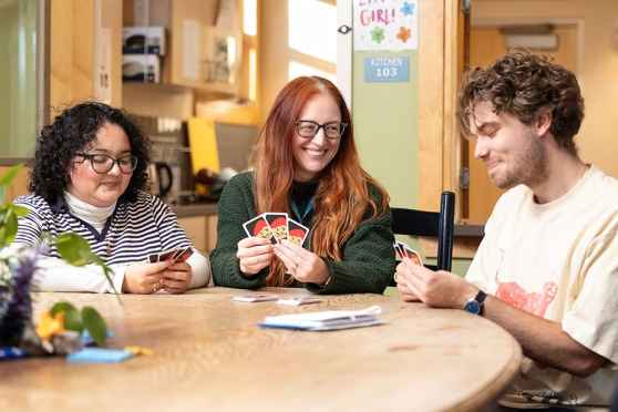 3 people playing Uno card game at 3East DBT program for teens and young adults
