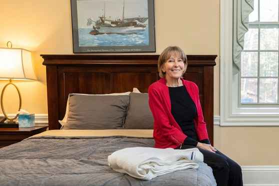 Woman in red jacket sits on bed