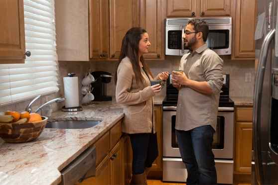 2 people standing with coffee cups in kitchen