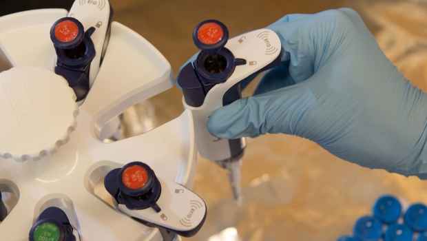 Researcher hand in blue glove reaches for research equipment