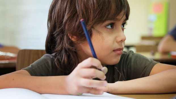 Kid at school holding pencil