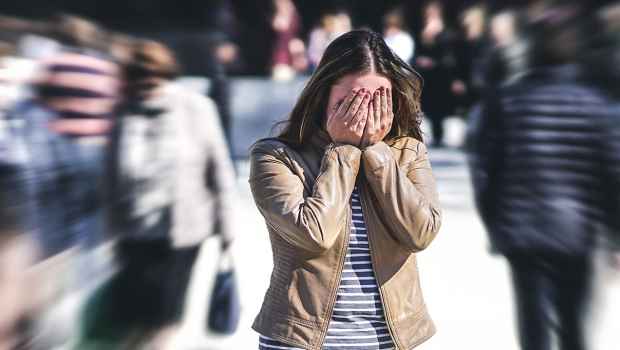 Young woman covers eyes in out of focus crowd