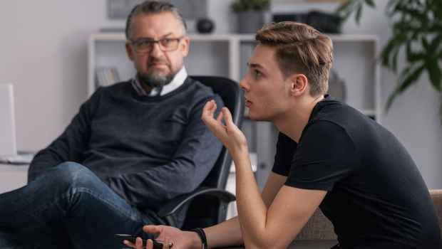 Teen boy in therapist office talking