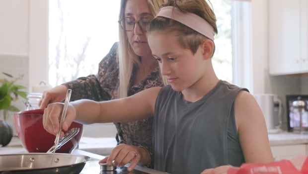 Young girl cooks with mom in kitchen